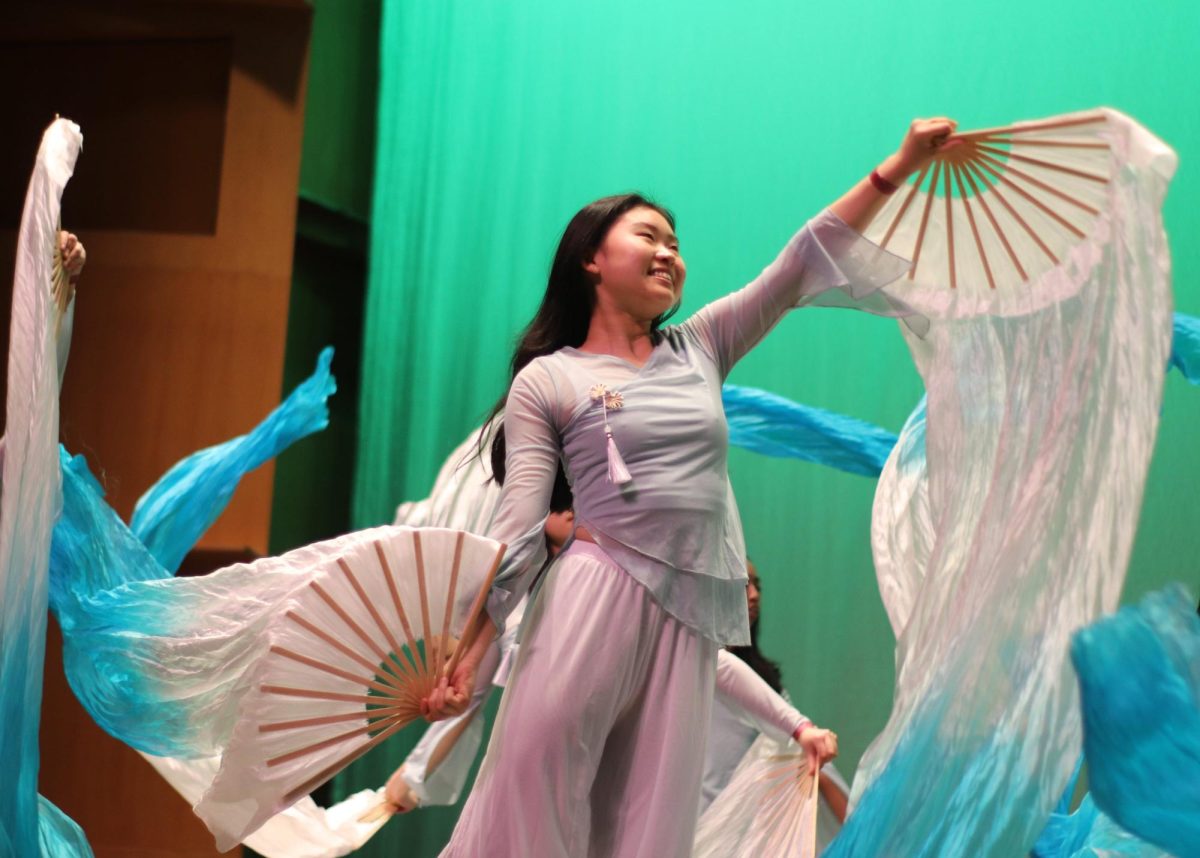 Flowing with the music, senior Yushu Zhang waves the fan with big, elegant movements in Chinese Honor Society’s performance. “It was refreshing to create memories with classmates and friends outside the school environment,” Zhang said.
