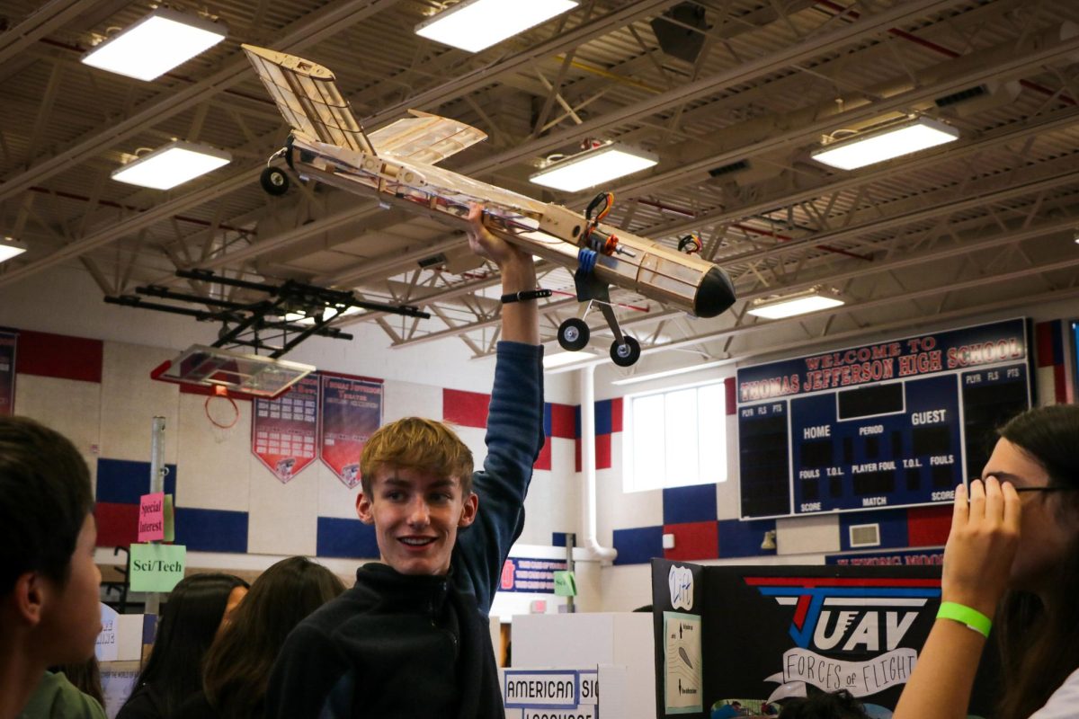 In an attempt to draw attention to the TJ Unmaned Arial Vehicle (UAV) booth at the Activity Fair, senior Niels-Oliver DeChaine holds up a prototype of a plane. “That one an alumn made for fun,” DeChaine said. “Our actual plane is ten feet wide and 50 pounds, so it's a lot bigger than that one. It's just a plane we had just to show off.” 