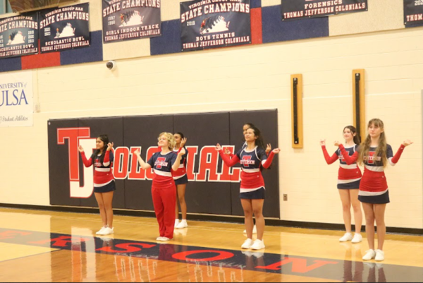 The red cheer team performs “The Jefferson Beat” while Jefferson’s basketball team runs the ball on the offensive. “The whole sport is very [good for] bonding within the team, even though I don’t have experience with other sports,” senior cheer captain Cricket Hicks said.