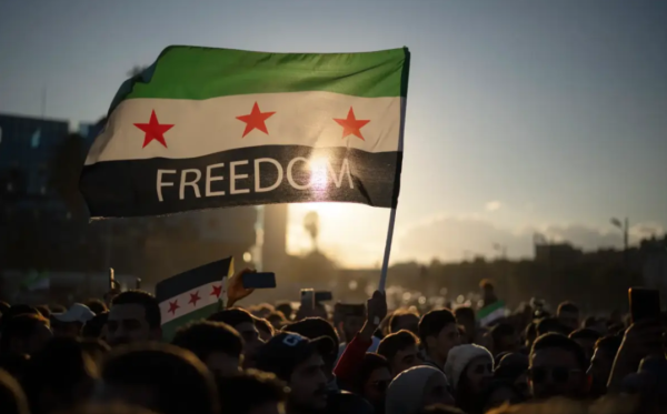 Syrians in the capital city, Damascus, wave revolutionary flags celebrating the country's newly found freedom.